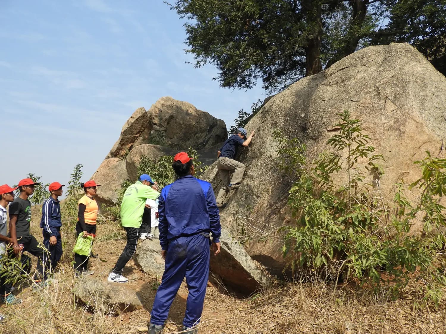 An instructor teaching a group of helmeted climbers on a boulder