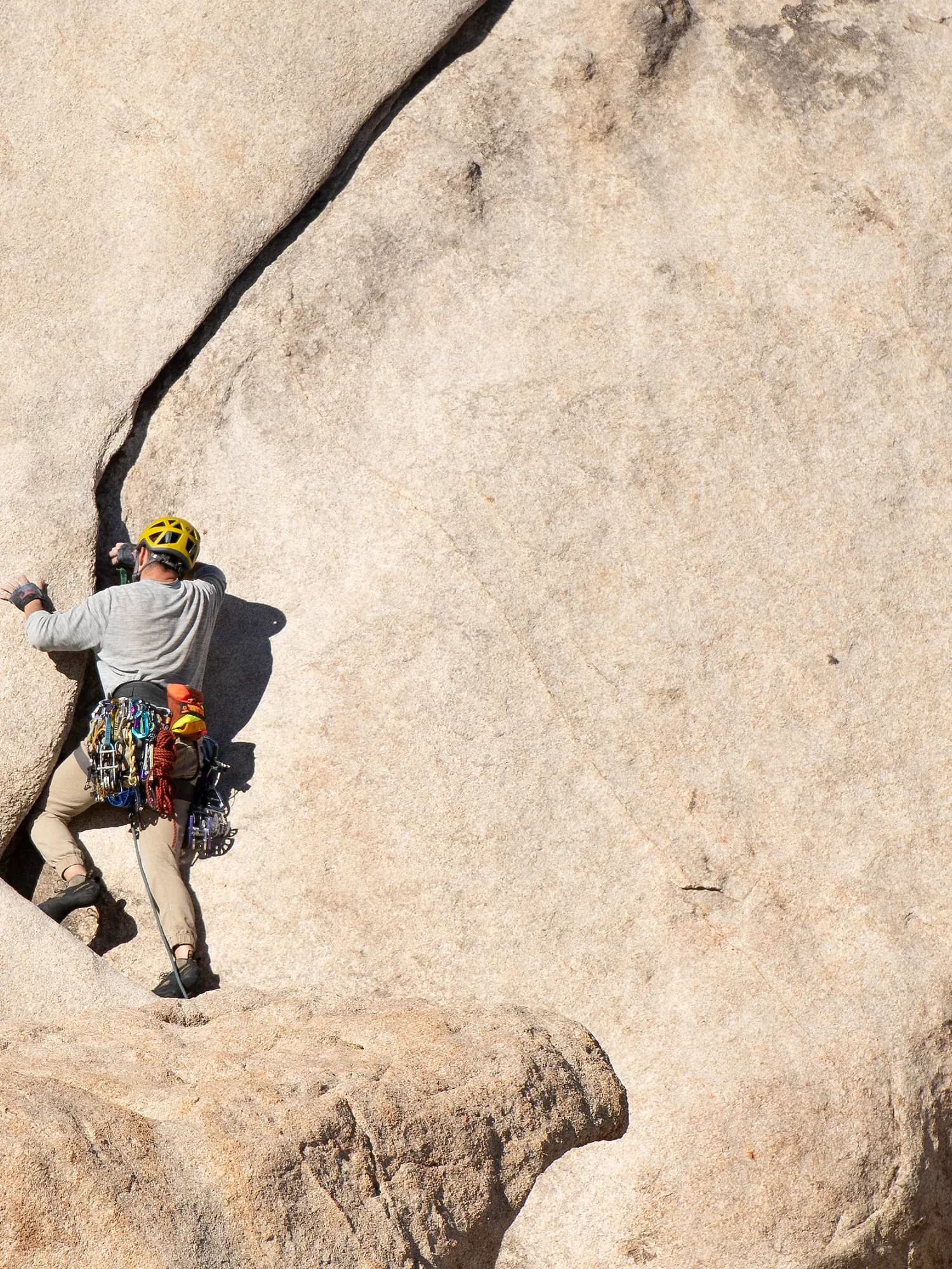 A helmeted climber moving up a granite crack line